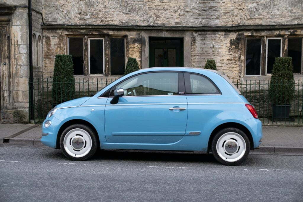 a blue car parked in front of a stone building